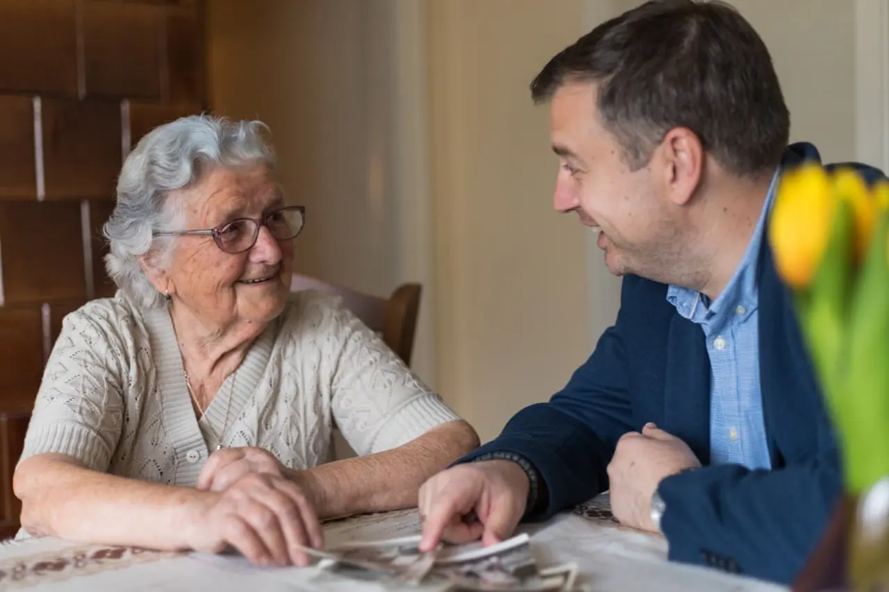 An elderly woman showing photos to a man