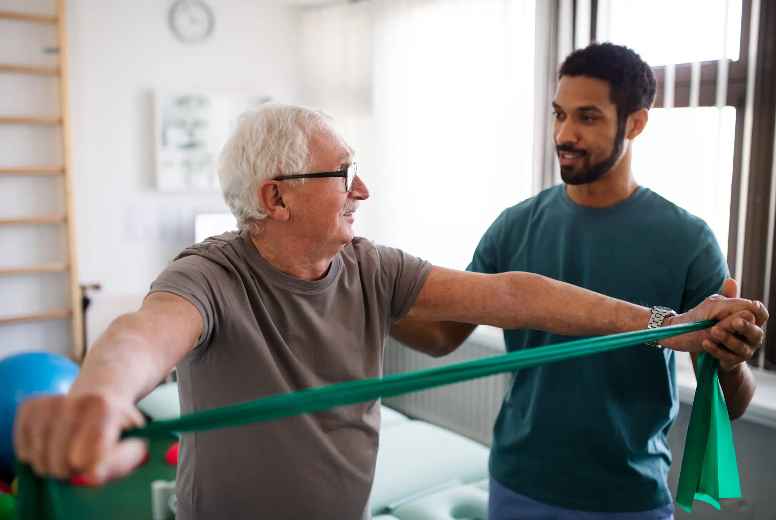 An old man getting help with his exercise routine in a senior living facility.